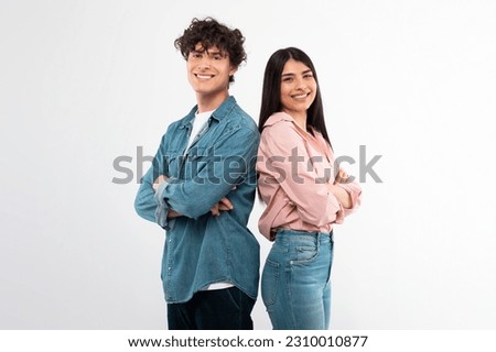 Cheerful Young Couple Crossing Hands In Confident Gesture Smiling To Camera Standing Back To Back Over White Studio Background. Happy Friendship And Love Relationship Concept Royalty-Free Stock Photo #2310010877