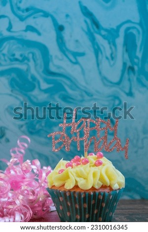 Iced birthday cupcake decorated with sprinkles on a colorful background