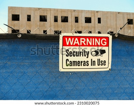 Construction site with security fence and warning sign of camera in use