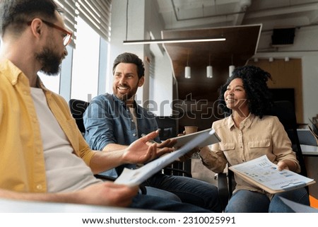 Inspired purposeful Hispanic bearded male manager, discussing business plans, sharing ideas, planning new startup project in a conference with business partners in meeting room in friendly atmosphere Royalty-Free Stock Photo #2310025991