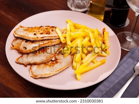 Close up of delicious baked pork with french fries, served at plate