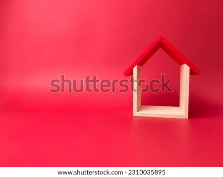 Wooden toy house on a red background with copy space.