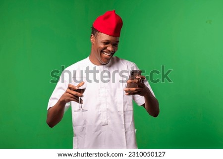 Photo of an African man enjoying a glass of wine and chatting on his cell phone