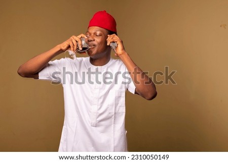 Photo of an African man enjoying a glass of wine and chatting on his cell phone