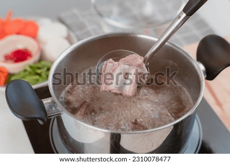 Homemade bouillon recipe. Chef's hands preparing pork rib stock (broth) with vegetables in the pot. Cook in the kitchen.