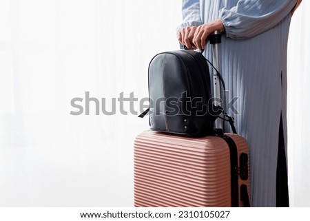 Close-up of a woman's hand holding a suitcase on a white background. A woman goes with a suitcase or bag on a trip. Vacation travel concept