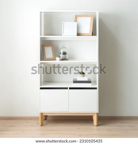 white shelving unit featuring a variety of small plants and two picture frames on the opposite side