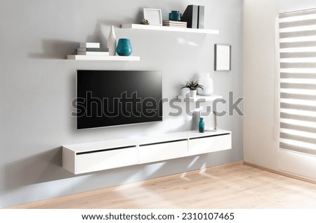a tv is in front of a shelf and some decorative items and framed photos