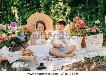 Happy kids boy and girl romantic picture in the park picnic with summer flowers. Boy and girl