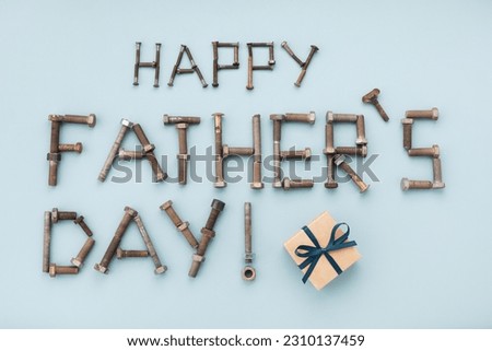 Happy fathers day greeting lettering text from vintage screws and gift box top view on blue background.
