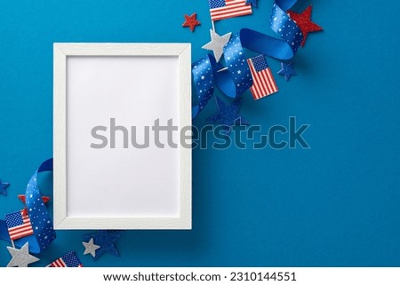 Patriotic-themed party accessories: curly ribbon, glitter stars, national flags, and empty photo frame. Top view on a blue background, featuring an empty space for text or advertisement
