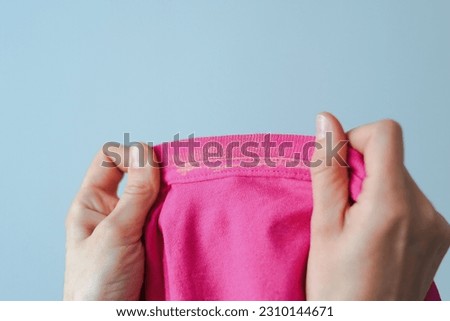 Hand showing dirty sweat and cosmetic stain on pink dressing. Visual evaluation of stains on clothes. Liquid foundation stains. daily life stain concept. High quality photo