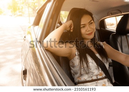 Beautiful Asian woman driving home during sunset, her face illuminated by the warm, golden rays of the descending sun. Concept of driving, travel and vacation