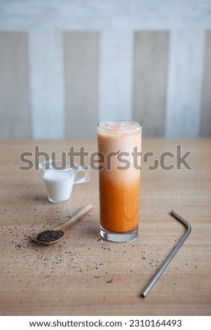 A glass of Thai Tea, fresh and sweet dessert on a wooden table