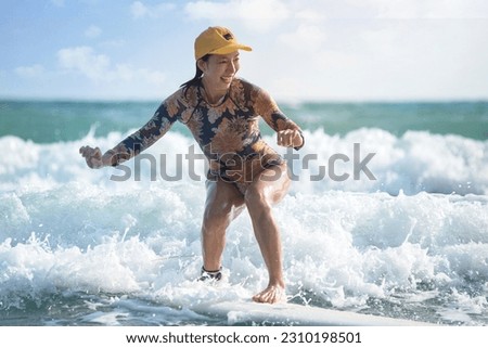 Asian surfing woman riding the waves on sunny day, outdoor activities, water sports activities concept Royalty-Free Stock Photo #2310198501