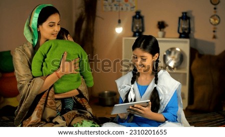 A village mother and a young schoolgirl in uniform using a digital tablet together. A happy family of a rural household spending quality time together in a traditional kitchen - village home, domes. Royalty-Free Stock Photo #2310201655