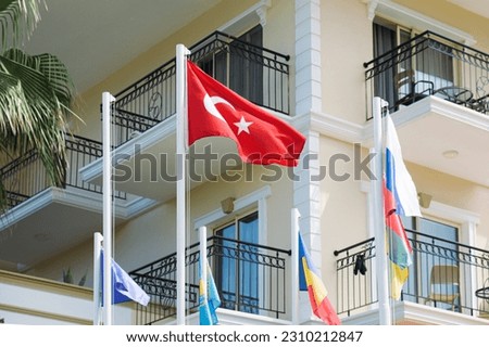 The flag of Turkey on a flagpole next to the flags of other states. Decoration of the entrance group of the hotel.