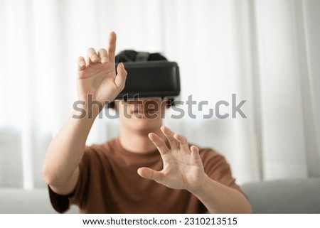 Young Asian man gamer wearing virtual reality touching air during the VR experience  Future home technology player hobby playful enjoyment concept