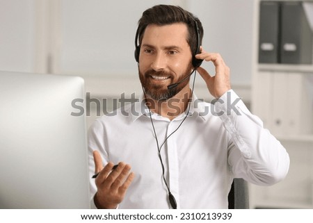 Hotline operator with headset working in office Royalty-Free Stock Photo #2310213939