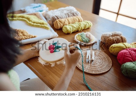 Punch needle. Asian Woman making handmade Hobby knitting in studio workshop. designer workplace Handmade craft project DIY embroidery concept Royalty-Free Stock Photo #2310216131
