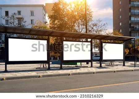 A large bus stop against the background of houses in a modern city with empty advertising banners inside. Template for design.