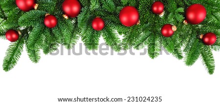 Studio isolated lush fir twigs with red baubles as a bow-shaped border on pure white background