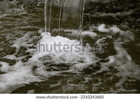 close up of water falling from a fountain and creating foam