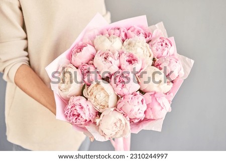 A bouquet of white and pink peonies in women's hands. Flower delivery. A beautiful bouquet of flowers as a gift for a holiday.