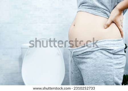woman with big abdomen in the toilet have problems with chronic constipation, lazy bowel syndrome, and  Digestive system concept  Royalty-Free Stock Photo #2310252733