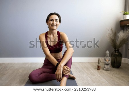 A beautiful woman rests after training. A clip shot of an attractive Asian woman resting after a morning workout in her modern room. The concept of healthy living