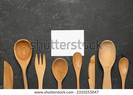 Composition with blank card and wooden cutlery on dark background