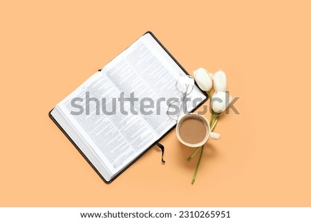 Open Holy Bible with tulip flowers and cup of coffee on orange background
