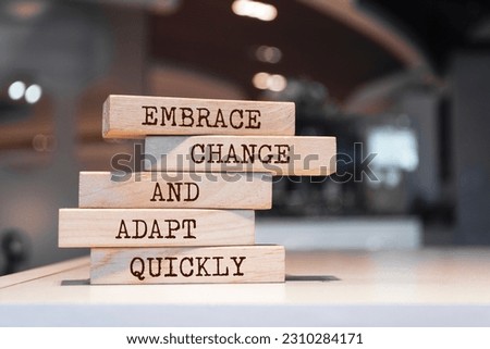 Wooden blocks with words 'Embrace change and adapt quickly'.