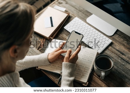 Unrecognizable business woman uses mobile phone and organizer for work.