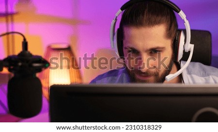 Close-up portrait of an esportsman. A professional gamer plays a computer video game, communicates in a headset with a team at the E-Sport championship. cyber gaming arena.