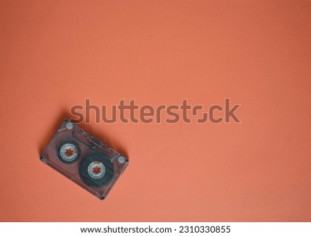 Audio cassette in the corner on brown background, top view.
