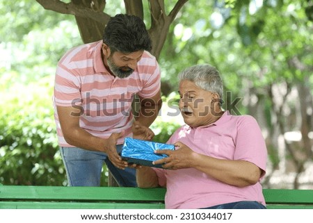 Indian happy son giving gift to happy father. father and son more celebrating and enjoying in garden