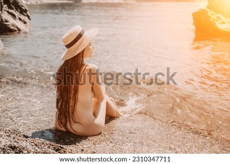 Woman travel sea. Happy tourist in hat enjoy taking picture outdoors for memories. Woman traveler posing on the beach at sea surrounded by volcanic mountains, sharing travel adventure journey