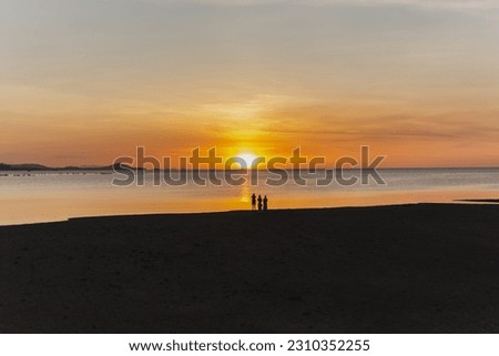 Silhouette of blurred people taking picture of sunset on the beach.