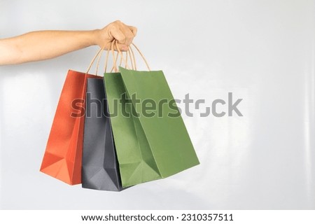 Hand holding paper shopping bag colorful three on white background. Royalty-Free Stock Photo #2310357511