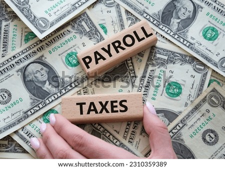 Payroll taxes symbol. Concept word Payroll taxes on wooden blocks. Beautiful dollar background. Businessman hand. Business and Payroll taxes concept. Copy space