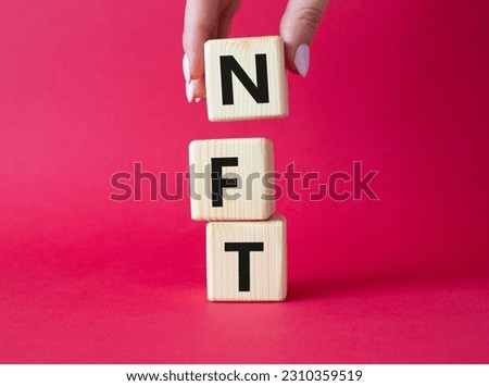 NFT - non-fungible token symbol. Concept word NFT on wooden cubes. Businessman hand. Beautiful red background. Business and NFT concept. Copy space.