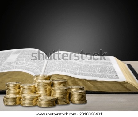 Holy Bible book and stack of coins