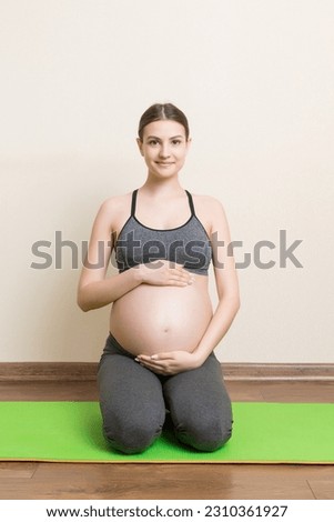Portrait of young pregnant yoga model working at the home. Pregnancy Yoga and Fitness concept at coronavirus time.