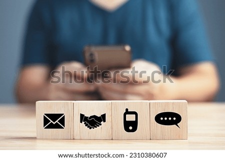 Businessmen using smartphones and contact icons on wooden blocks (chat, phone, shakehand, email), Contact us and Customer support hotline people connect.