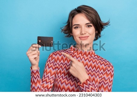 Photo portrait of lovely young lady hold credit card point finger wear trendy striped garment isolated on blue color background