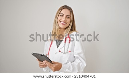 Young blonde woman doctor smiling confident using touchpad over isolated white background