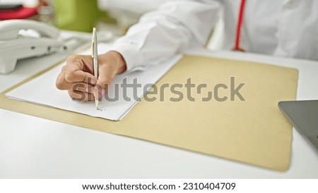 Young blonde woman doctor writing medical report at clinic