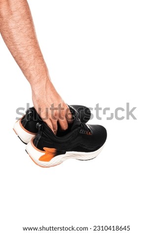 Pair of new unbranded black sport running shoes or sneakers in male hand isolated on white background with clipping path. High quality photo