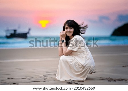 Asian women Sit and take photos at the sandy beach in the evening. with a fishing boat in the background. Use AI to help with processing.